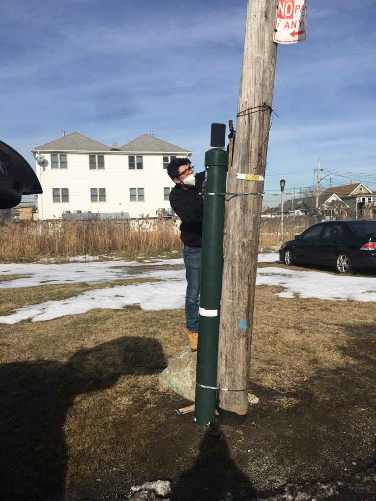 Person setting up FloodNet sensor on a pole.