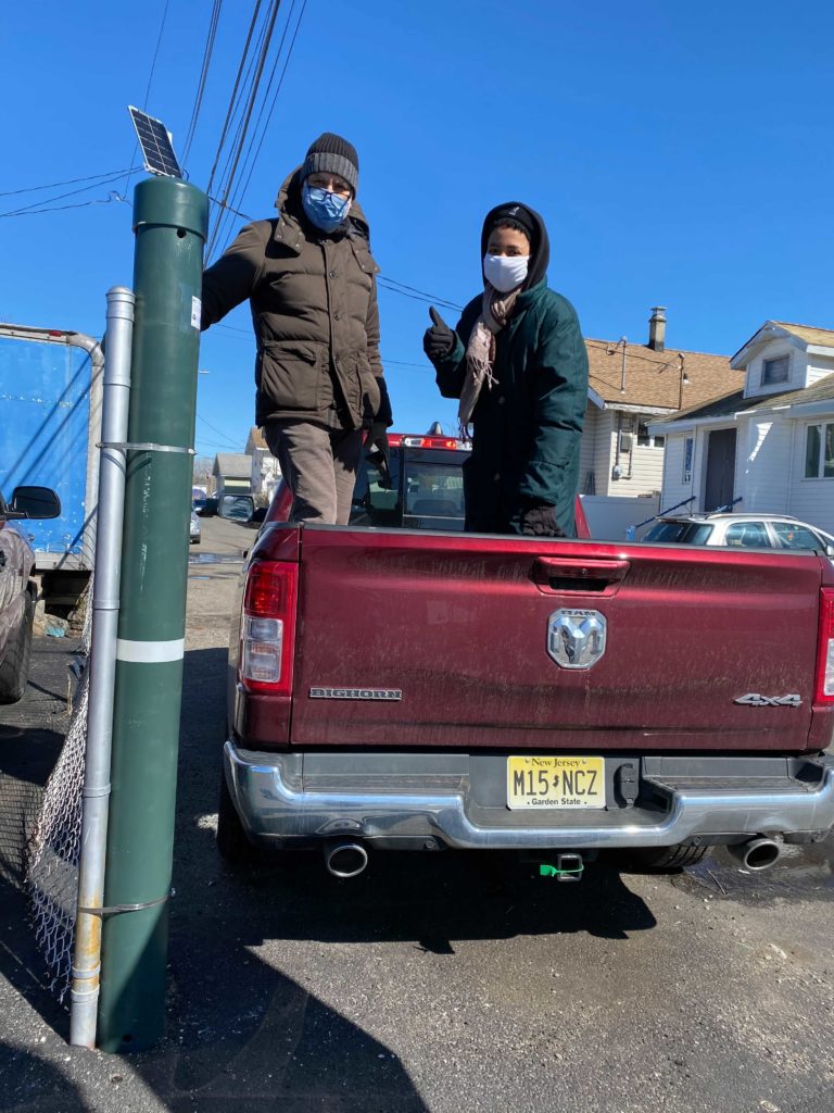 Two people standing next to sensor pole on a red truck.